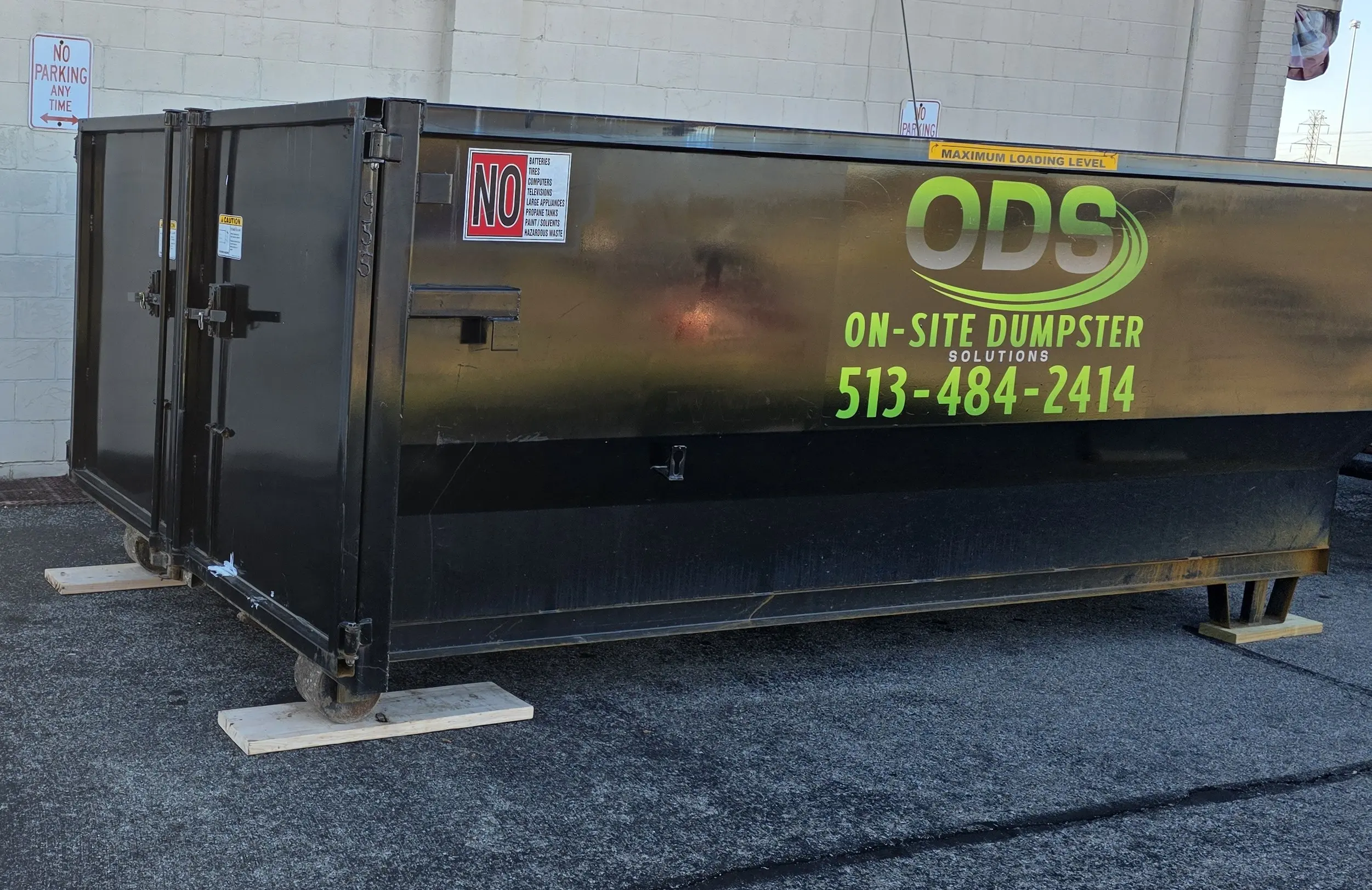 On-Site Dumpster Solutions roll-off container resting safely on protective wood blocks.